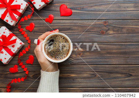Flat lay of heart shaped cup of black coffee in the hands of women on colored background with copy space top view. Valentine day and holiday concept 110407942