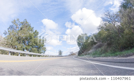Vehicle is cruising along the Cuyama Highway under the bright sun. The surrounding landscape is illuminated by the radiant sunshine, creating a picturesque and inviting scene as the car travels Vehicle is cruising along the Cuyama Highway under the bright sun. The surrounding landscape is illuminated by the radiant sunshine, creating a picturesque and inviting scene as the car travels 110407961