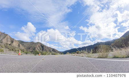 Vehicle is cruising along the Cuyama Highway under the bright sun. The surrounding landscape is illuminated by the radiant sunshine, creating a picturesque and inviting scene as the car travels Vehicle is cruising along the Cuyama Highway under the bright sun. The surrounding landscape is illuminated by the radiant sunshine, creating a picturesque and inviting scene as the car travels 110407976