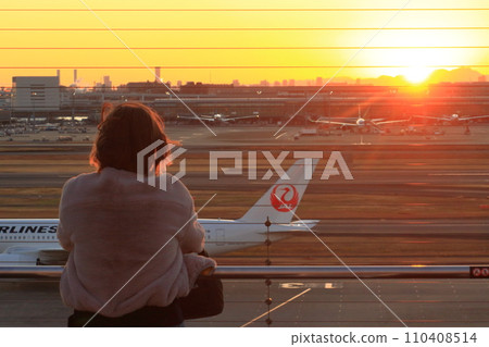 一位女士在日落時看著機場。機場的黃昏 110408514