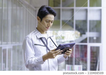 一名穿著工作服的年輕人看著平板電腦。攝影由有明教育藝術學院提供。 110408589