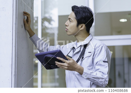 一名穿著工作服的年輕人一邊查看平板電腦一邊檢查建築物。照片由有明教育藝術學院提供。 一名穿著工作服的年輕人一邊查看平板電腦一邊檢查建築物。照片由有明教育藝術學院提供。 110408686