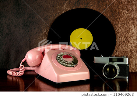 Vintage Telephone with Film Camera and Long Playing Record on a Polished Wooden Table Top 110409268