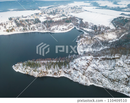 Sec water reservoir with concrete dam and wintertime snowy hills of Iron Mountains around. Czechia. Aerial view from drone. 110409510
