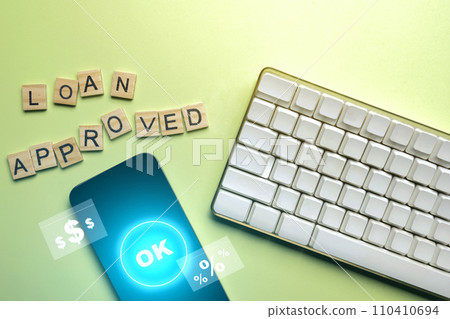 Computer keyboard with a mobile phone and a wooden cube with a Loan Approved letter 110410694