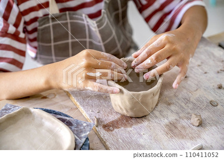 Kids making a craft of a porcelain mug from wet clay 110411052