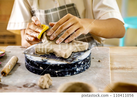 Kids making a craft of a porcelain mug from wet clay 110411056