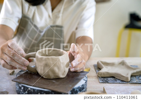 Kids making a craft of a porcelain mug from wet clay 110411061