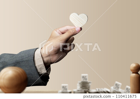 The businessman's hand shows a wooden heart with a rate symbol 110411675