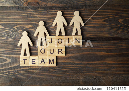 Wooden figures and wooden cubes with Join Our Team letters on a wooden table 110411835