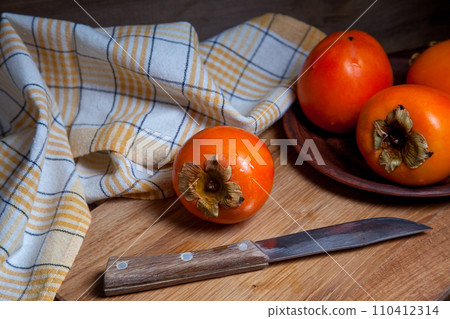 Whole ripe persimmon on a wooden background.. 110412314