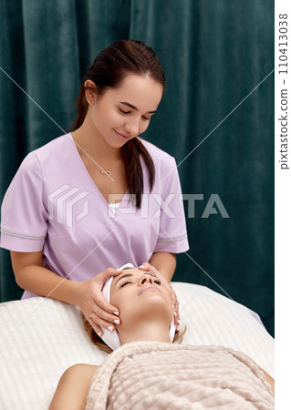 Beautiful woman getting face massage treatment in beauty salon. girl enjoys this procedure. Beautiful woman getting face massage treatment in beauty salon. girl enjoys this procedure. 110413038