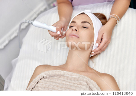 cosmetologist making procedure microdermabrasion on the face in beauty salon. professional skin care cosmetologist making procedure microdermabrasion on the face in beauty salon. professional skin care 110413040