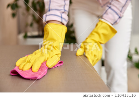 young woman in gloves cleaning and wiping table with microfiber cloth. chores at home. Housekeeping young woman in gloves cleaning and wiping table with microfiber cloth. chores at home. Housekeeping 110413110