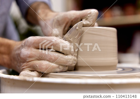 male hands making ceramic cup on pottery wheel with special wooden tool, Close-up 110413148