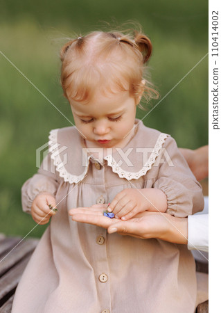 A child takes a flower from an adult's hand A child takes a flower from an adult's hand 110414002