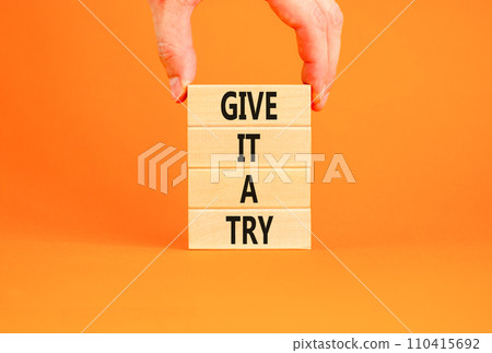 Give it a try symbol. Concept word Give it a try on beautiful wooden block. Beautiful orange table orange background. Businessman hand. Business give it a try concept. Copy space. 110415692
