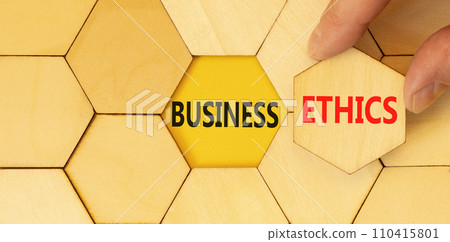 Business ethics symbol. Concept words Business ethics on beautiful wooden puzzle. Beautiful yellow table yellow background. Businessman hand. Business ethics concept. Copy space. Business ethics symbol. Concept words Business ethics on beautiful wooden puzzle. Beautiful yellow table yellow background. Businessman hand. Business ethics concept. Copy space. 110415801