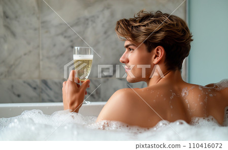 AI-generated content. International Quirkyalone Day, February 14. Handsome Young Man Drinks Glass of Champagne and Enjoying Time in Bathtub with Bath Foam in Modern Bathroom. AI Generated Horizontal 110416072