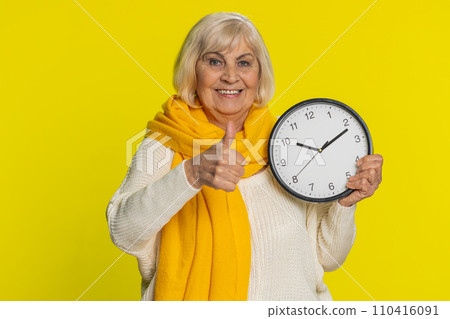 Senior old woman showing time hour on wall office clock, ok, thumb up, approve, hurry up, deadline Senior old woman showing time hour on wall office clock, ok, thumb up, approve, hurry up, deadline 110416091