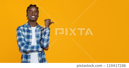 Handsome young black man in plaid shirt pointing aside to empty space Handsome young black man in plaid shirt pointing aside to empty space 110417286