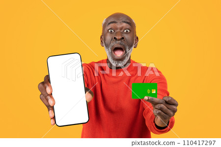 Shocked funny old black man with open mouth show credit card and phone with blank screen 110417297
