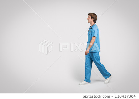 Male medical professional in scrubs walking, side view 110417304