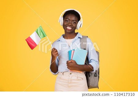 Glad millennial black lady student in wireless headphones, with books, flag of Italy 110417310