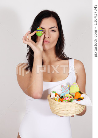 Beautiful woman with a basket of Easter desserts Beautiful woman with a basket of Easter desserts 110417345