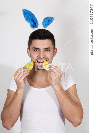 Handsome young man in rabbit ears on a white background. Easter concept Handsome young man in rabbit ears on a white background. Easter concept 110417347