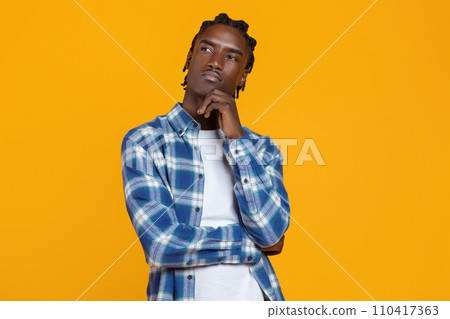 Portrait of thoughtful young black man touching chin and looking away 110417363