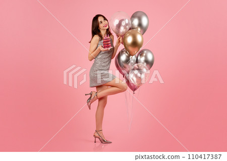 A playful woman with a bright smile, dressed in a shimmering silver dress A playful woman with a bright smile, dressed in a shimmering silver dress 110417387