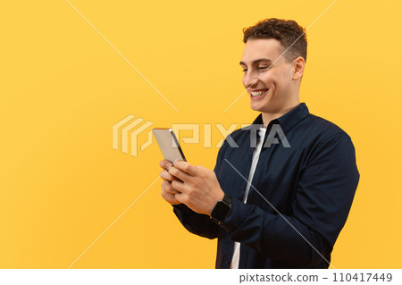 Positive guy using smartphone on yellow background 110417449