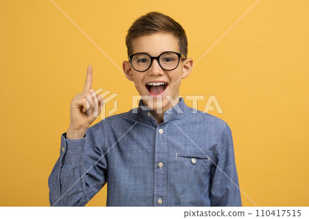 Enthusiastic teen boy wearing glasses pointing upwards with finger 110417515