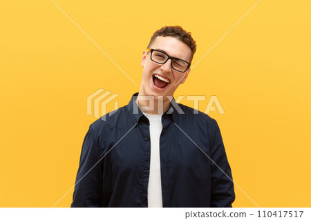 Playful young blonde guy posing on yellow background 110417517