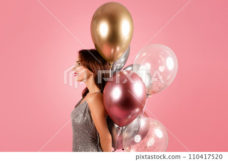 A serene woman in a sparkling silver dress gazes into the distance, her profile 110417520