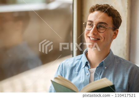Glad calm handsome european young man student in glasses read book, enjoy peace 110417521