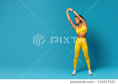 Athletic Black Woman Doing Side Bend With Raised Arms, Studio 110417525