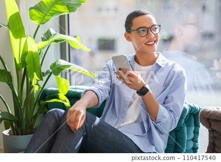 Cheerful young latin lady in glasses enjoy peace and spare time, typing on mobile phone 110417540