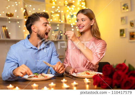 Woman feeding man pasta at romantic candlelit dinner 110417579