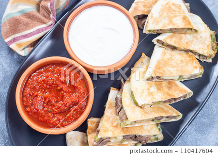 Fajita quesadilla with pieces of beef steak, green bell pepper, onion and cheese, top view Fajita quesadilla with pieces of beef steak, green bell pepper, onion and cheese, top view 110417604