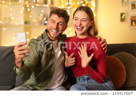 Couple taking selfie during romantic proposal at home 110417607