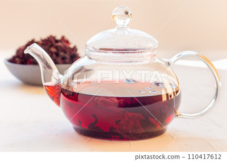 Red tea karkade or hibiscus in glass tea pot and on plate, horizontal Red tea karkade or hibiscus in glass tea pot and on plate, horizontal 110417612