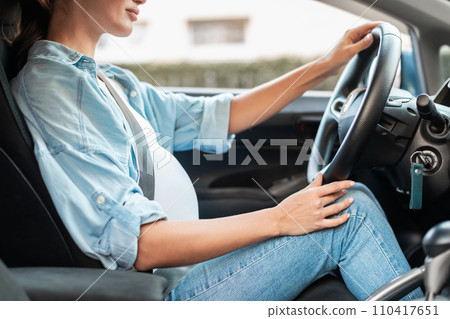 Cropped shot of pregnant woman driving auto sitting in car Cropped shot of pregnant woman driving auto sitting in car 110417651