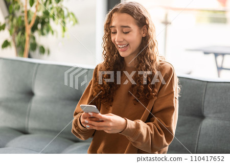 teen girl websurfing on cellphone engaged in online leisure indoor teen girl websurfing on cellphone engaged in online leisure indoor 110417652