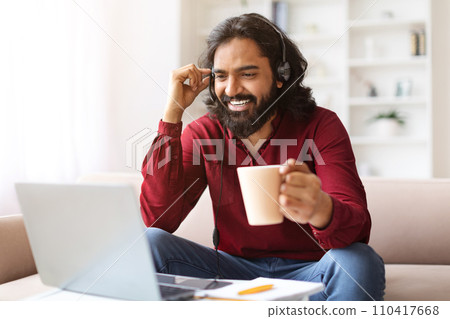 Smiling millennial eastern guy studying online from home Smiling millennial eastern guy studying online from home 110417668