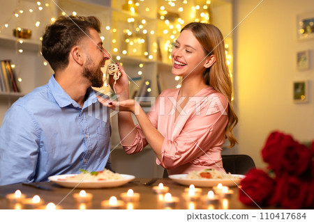 Joyful couple sharing pasta at a candlelit dinner 110417684