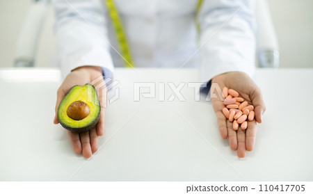 Doctor hands full of capsules supplements and fresh avocado Doctor hands full of capsules supplements and fresh avocado 110417705