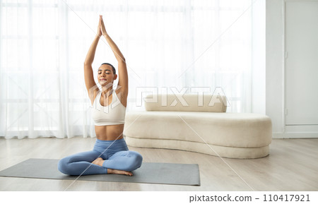Focused Hispanic woman practicing the lotus pose with hands in namaste during a tranquil yoga 110417921