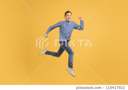 Dynamic teen boy jumping in air against yellow studio background Dynamic teen boy jumping in air against yellow studio background 110417922